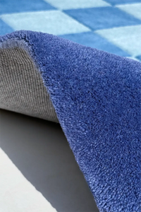 Close-up of a blue textured rug with a checkered pattern in the background