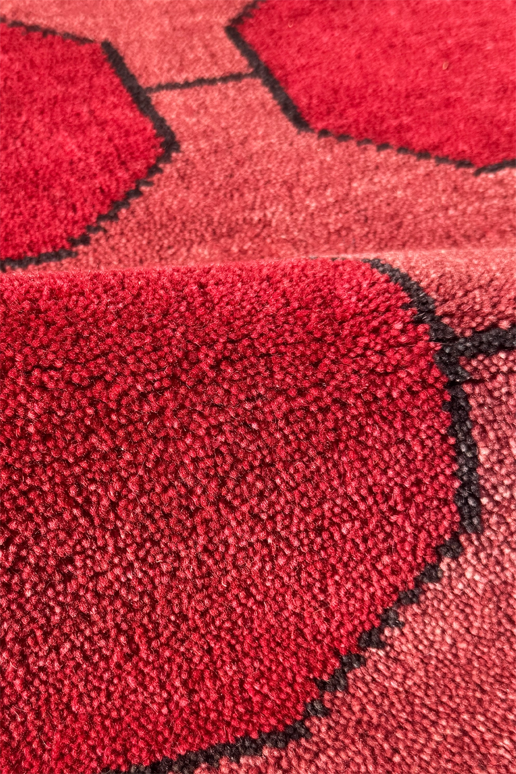Close-up of a red geometric patterned wool rug with black accents