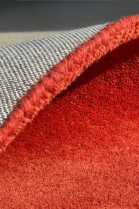 Close-up of a thick red textured rug with gray cotton backing.