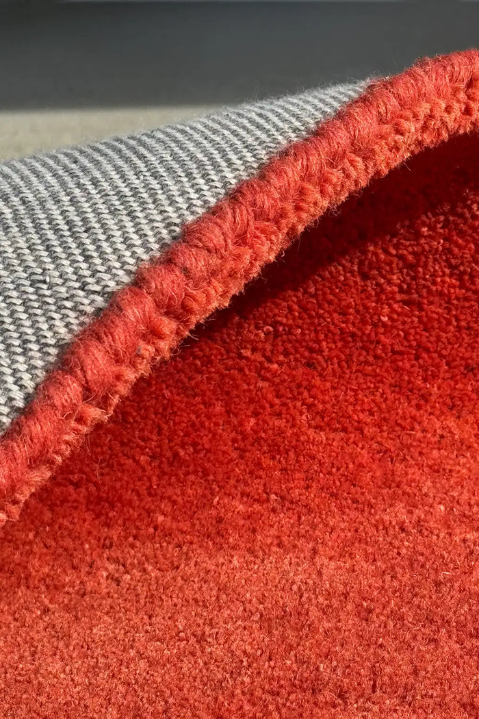 Close-up of a thick red textured rug with gray cotton backing.