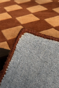 bound edge of brown wool rug hand-tufted with geometric diamond checkerboard pattern