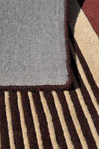 Hand-tufted wool rug in brown, rust, and tan with multicolored linear pattern
