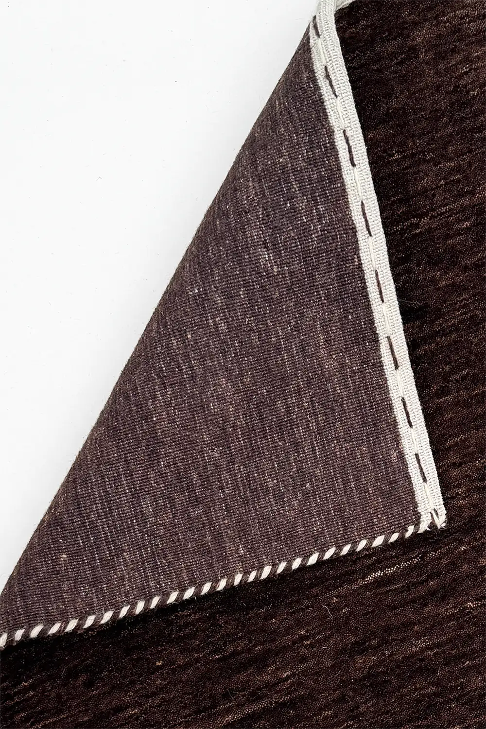 Close-up of a deep brown rug with white stitching on a white background