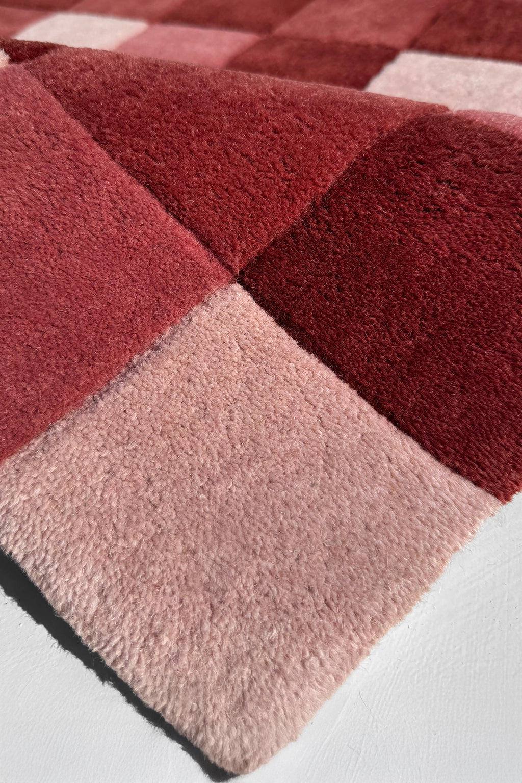 Close-up of a textured red and pink rug with geometric checkered pattern