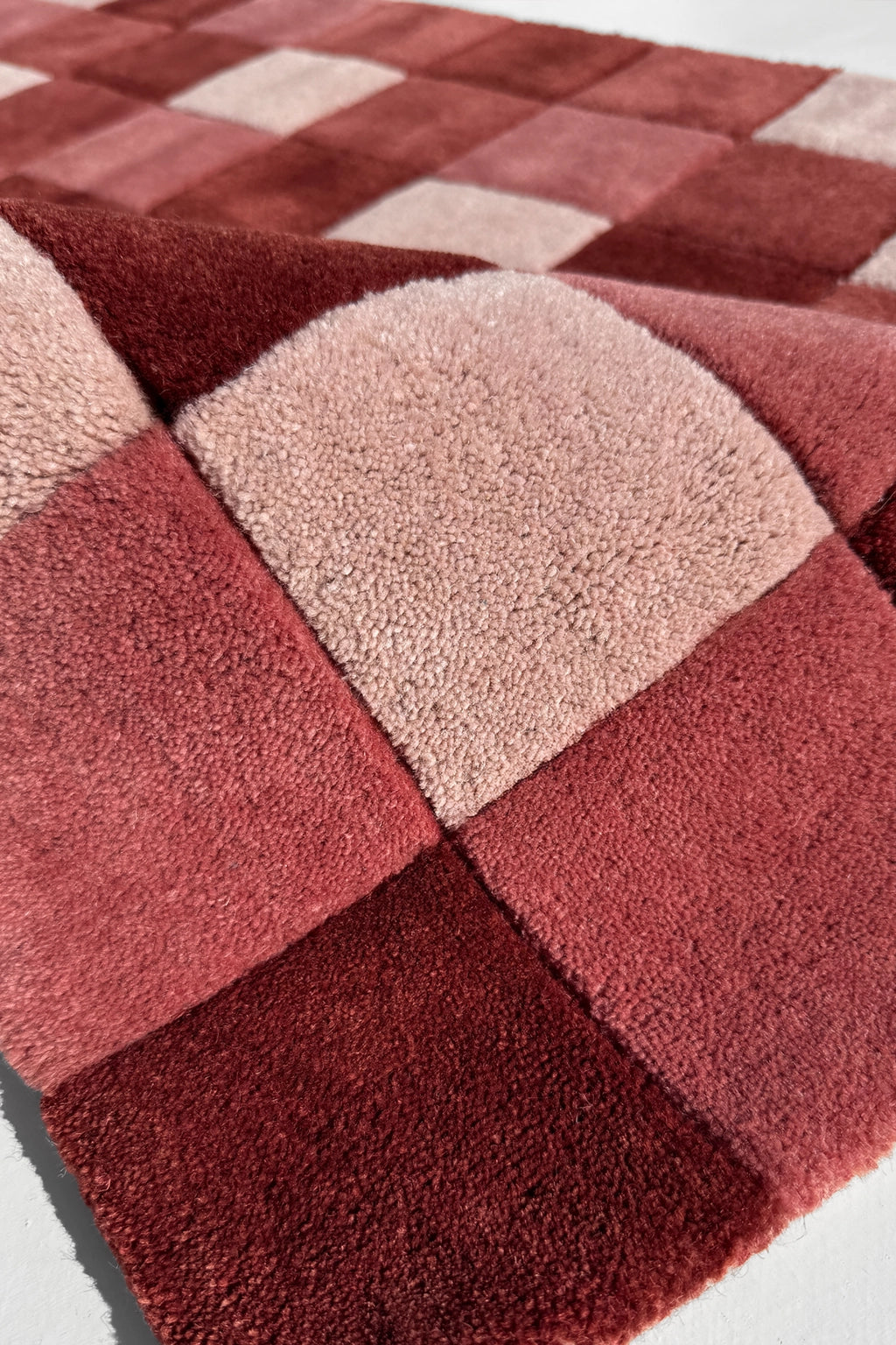 Checkered red and beige rug on a white background