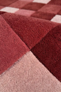 Close-up of a textured burgundy red and pink checkered rug
