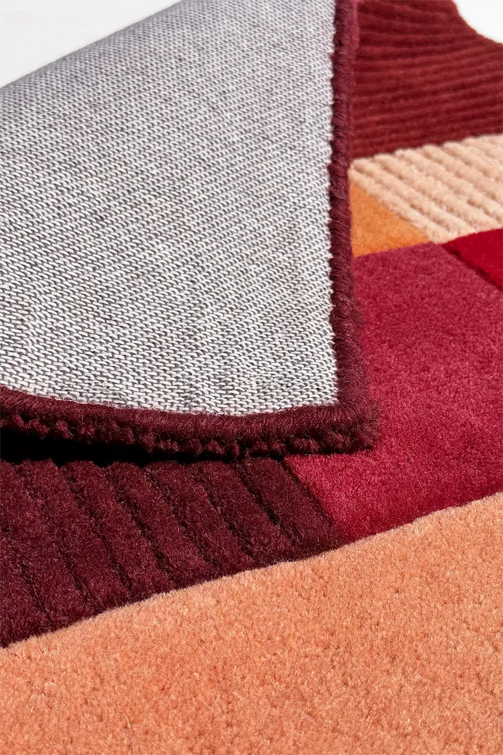 Close-up of a textured fabric with a geometric pattern in red, orange, and burgundy.