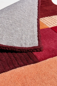 Close-up of a textured fabric with a geometric pattern in red, orange, and burgundy.