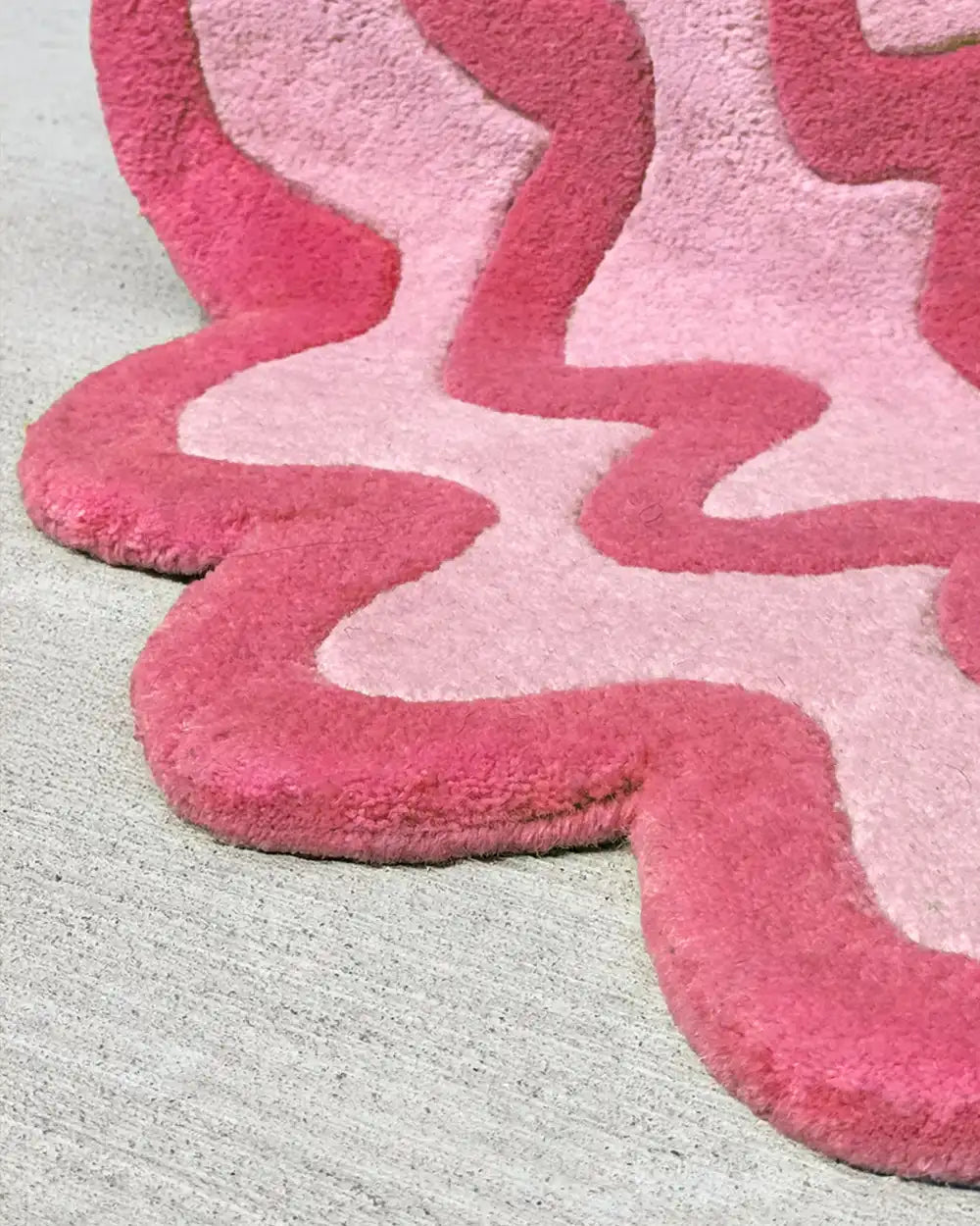colorful wool area rug in light and dark pink with unique wavy edges and ripple design