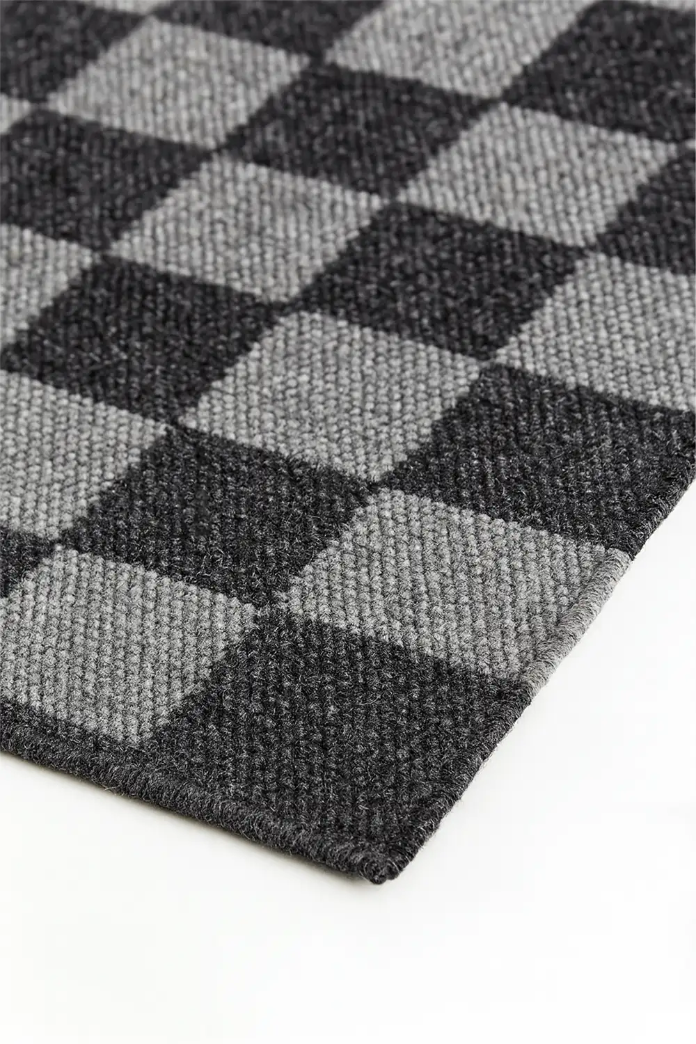 Close-up of a checkered black and gray woven wool rug on a white surface