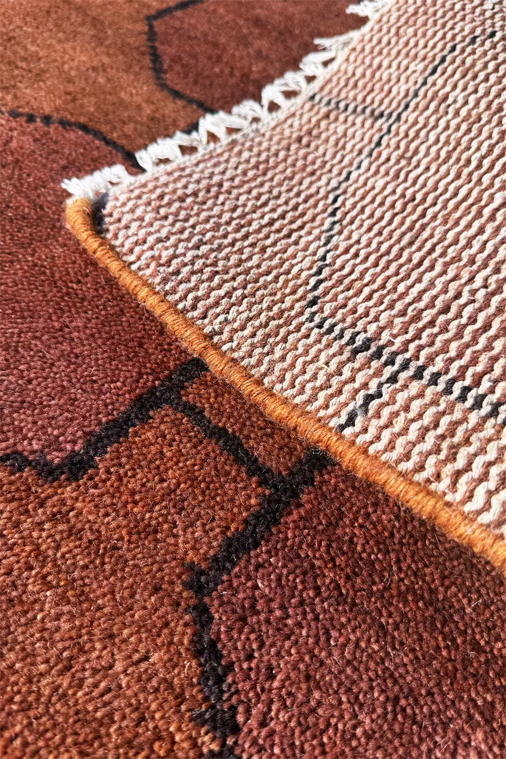 Close-up of a textured rust brown rug with geometric patterns.