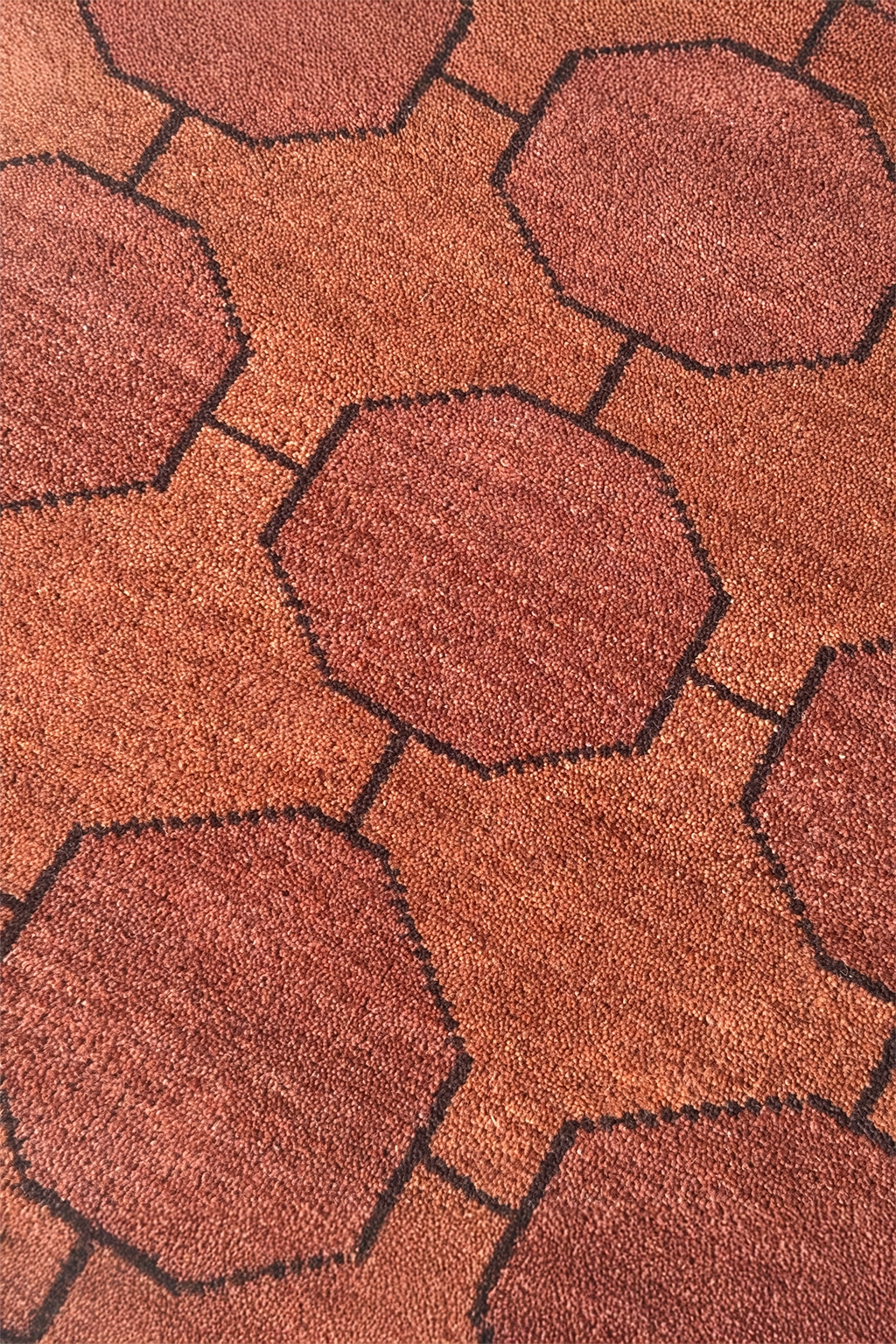 Close-up of a textured chestnut wool rug with geometric patterns
