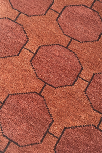 Close-up of a textured chestnut wool rug with geometric patterns
