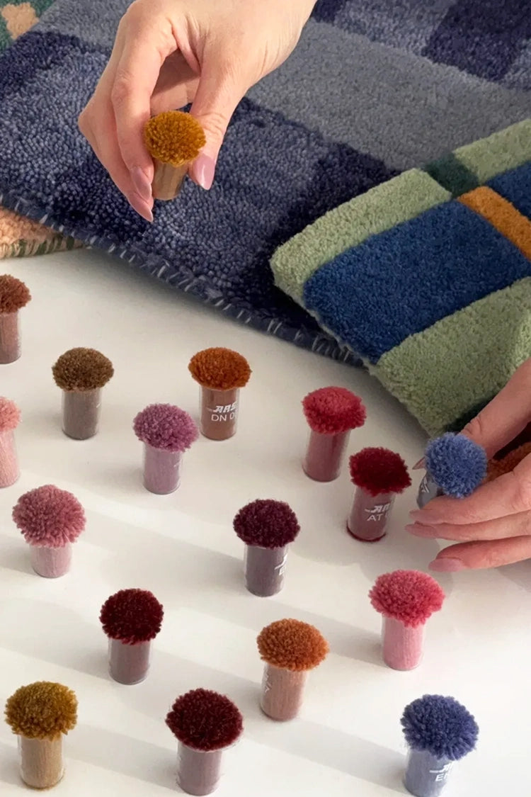 Color swatches with pom-pom textures on a white surface, with a hand holding a textured sample.