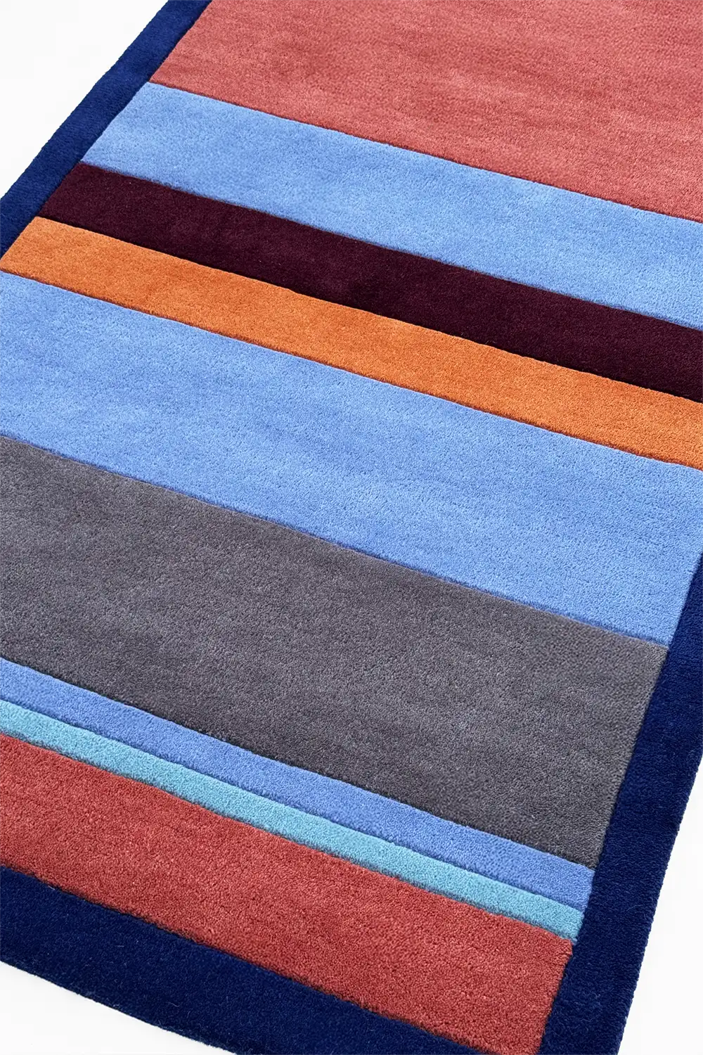 Multicolored striped rug with blue, red, orange, and gray stripes on a white background lifestyle