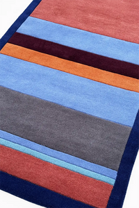 Multicolored striped rug with blue, red, orange, and gray stripes on a white background lifestyle