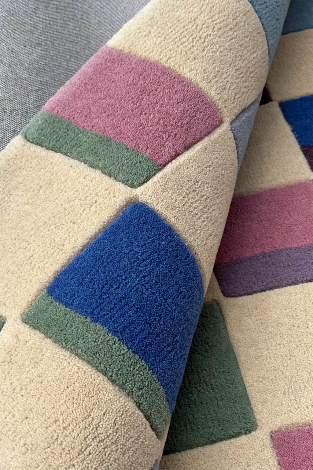 Close-up of a textured square rug with colorful geometric patterns