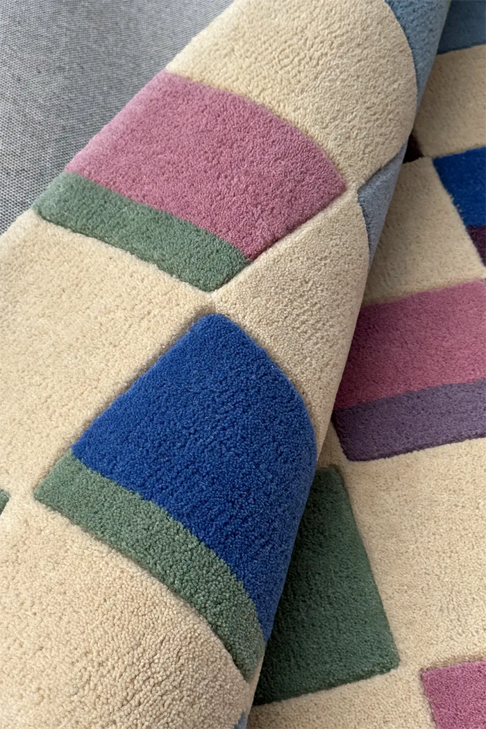 Close-up of a textured square rug with colorful geometric patterns