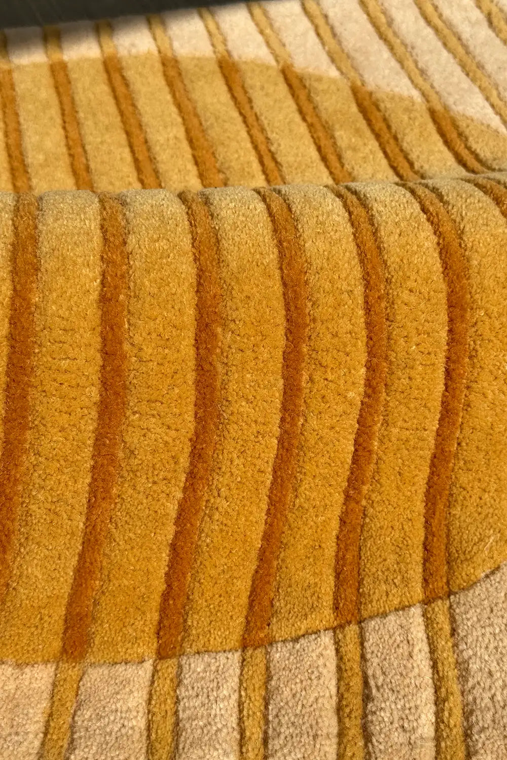 Close-up of a textured yellow and beige hand-tufted square carpet