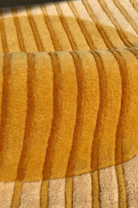 Close-up of a textured yellow and beige hand-tufted square carpet