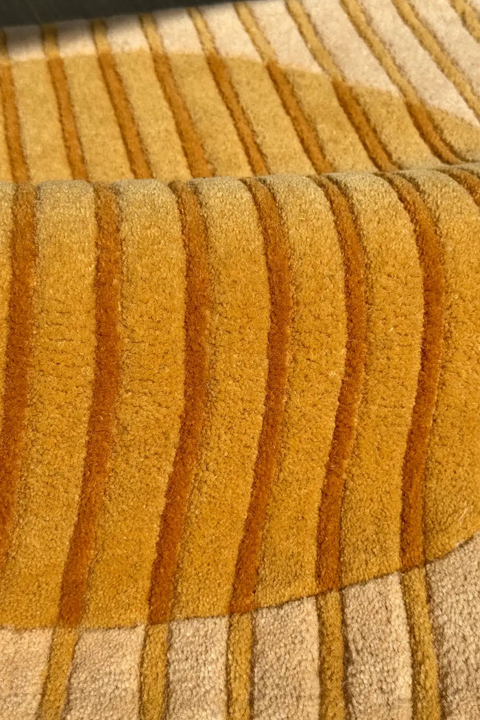 Close-up of a textured yellow and beige hand-tufted square carpet