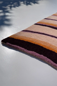 Striped rug with pink, orange, and purple colors on a light gray floor.
