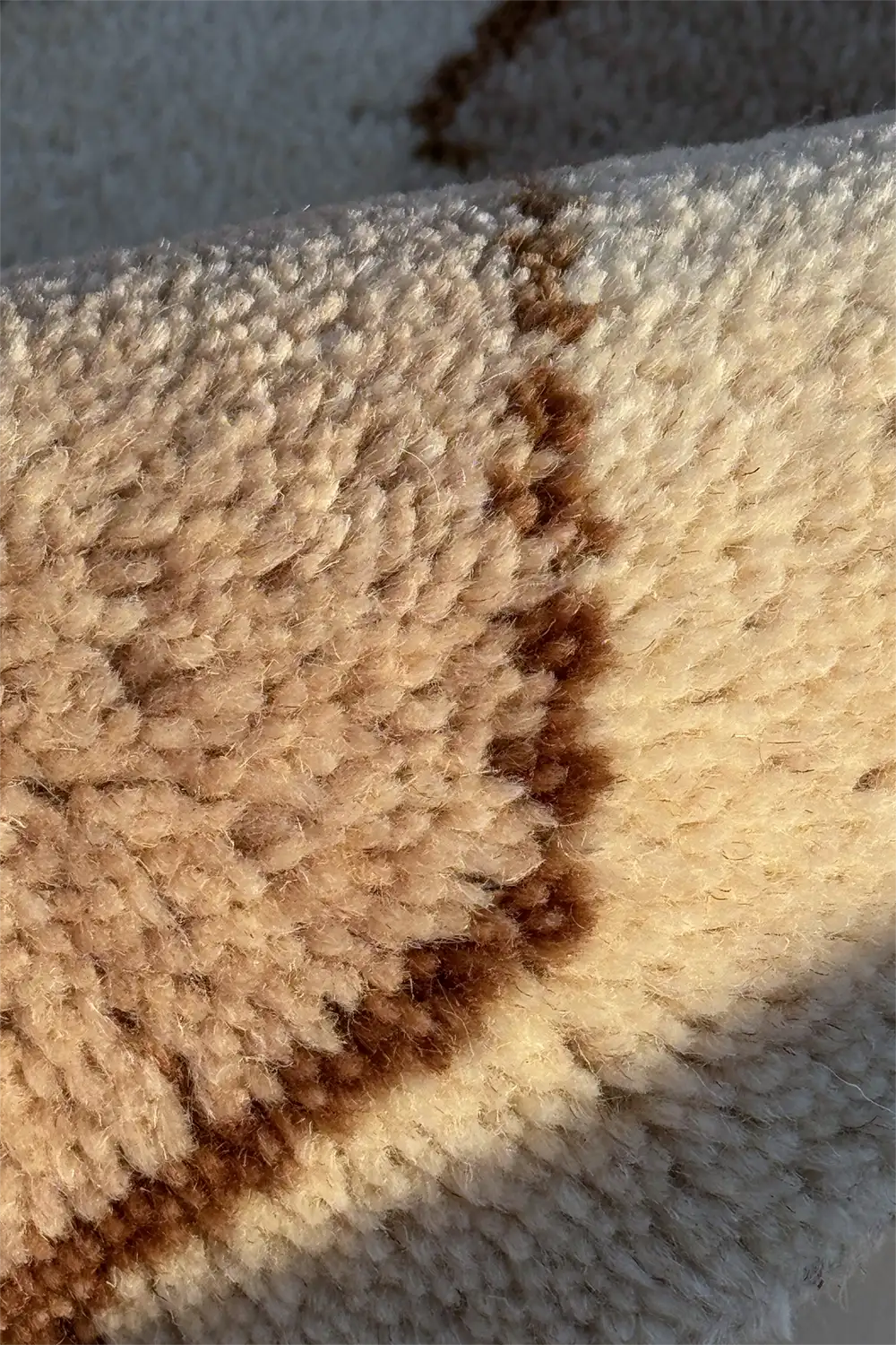 Close-up of a beige wool carpet with brown knotted design ivory