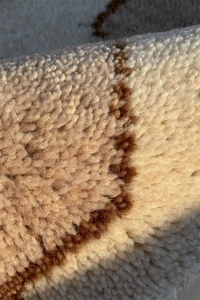 Close-up of a beige wool carpet with brown knotted design ivory