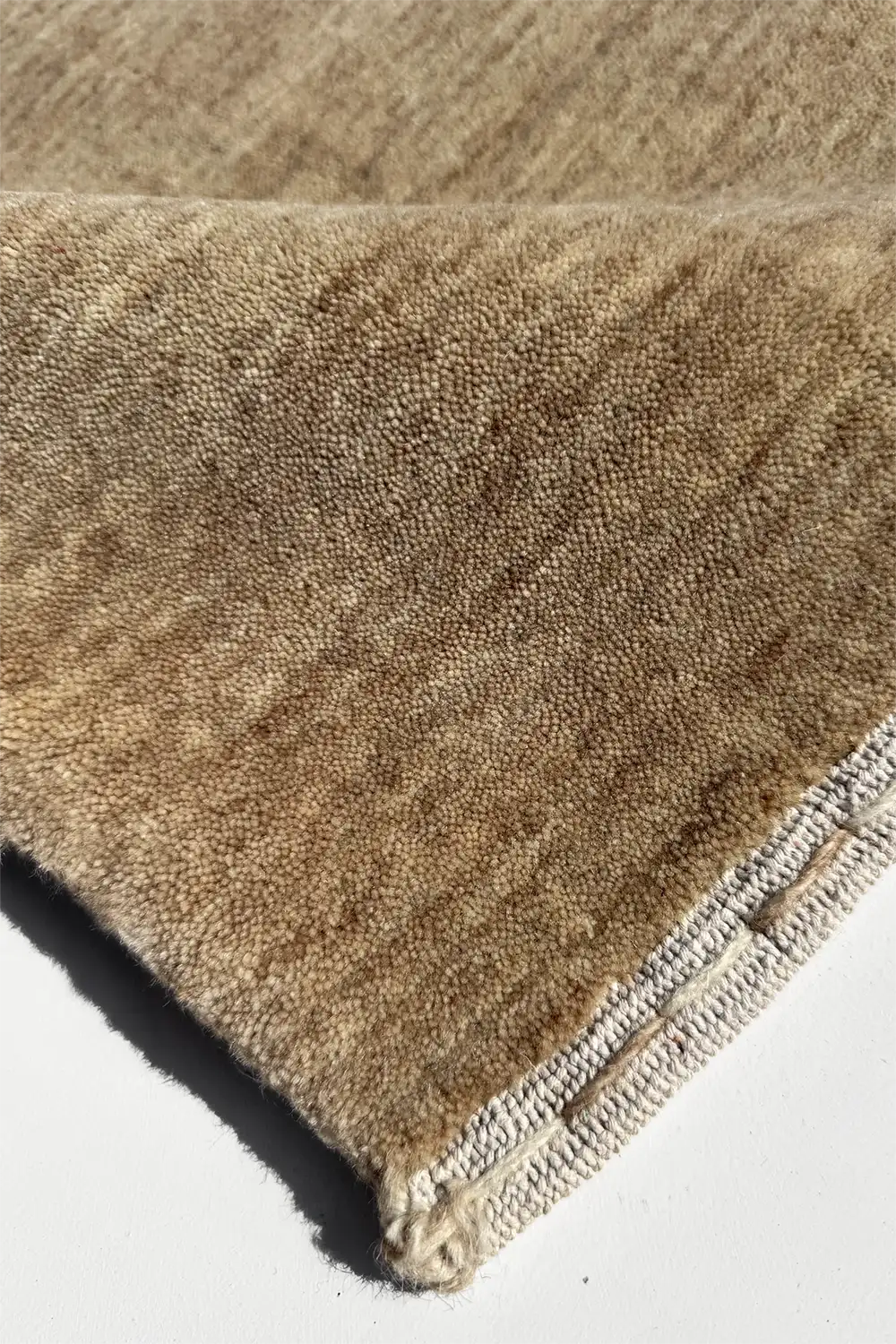 Close-up of a brown textured rug corner on a white background