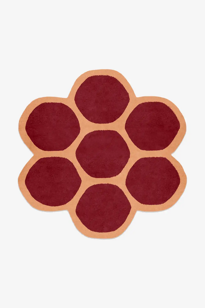 Round rug with a flower pattern in red and orange on a white background