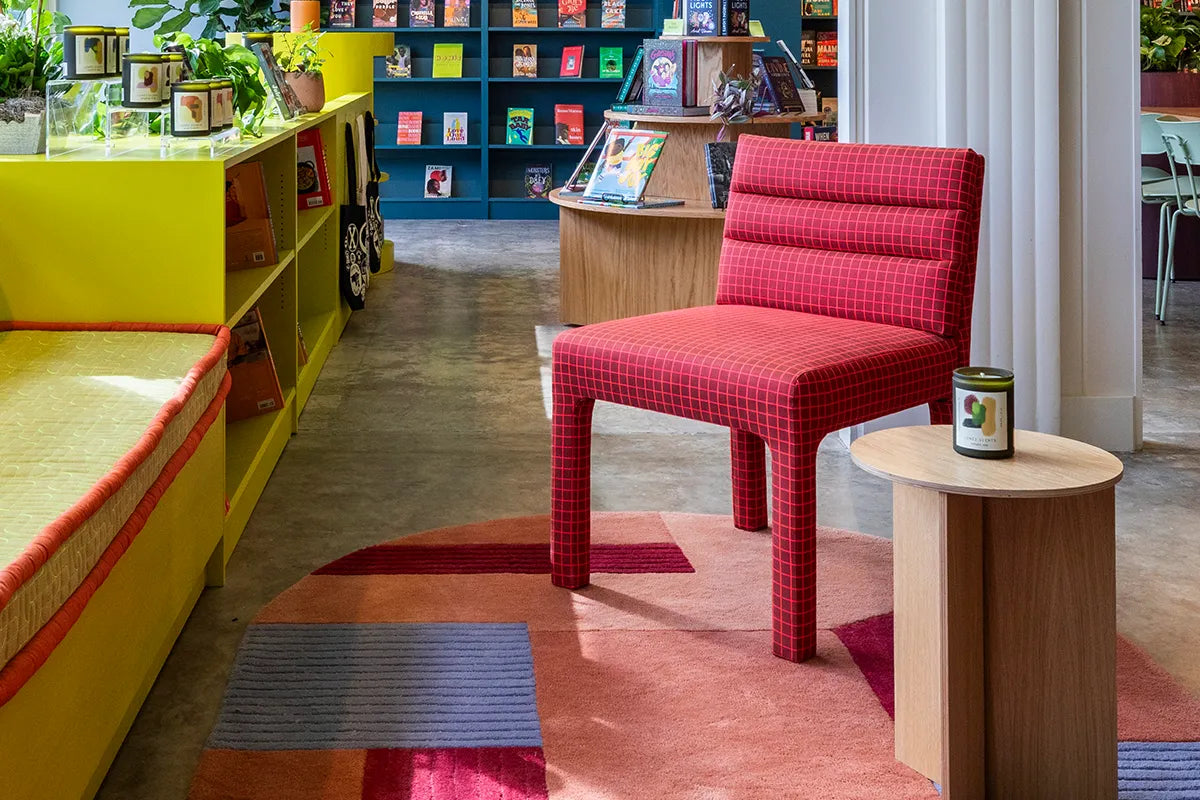 Modern interior with a red chair, colorful rug, and bookshelf.