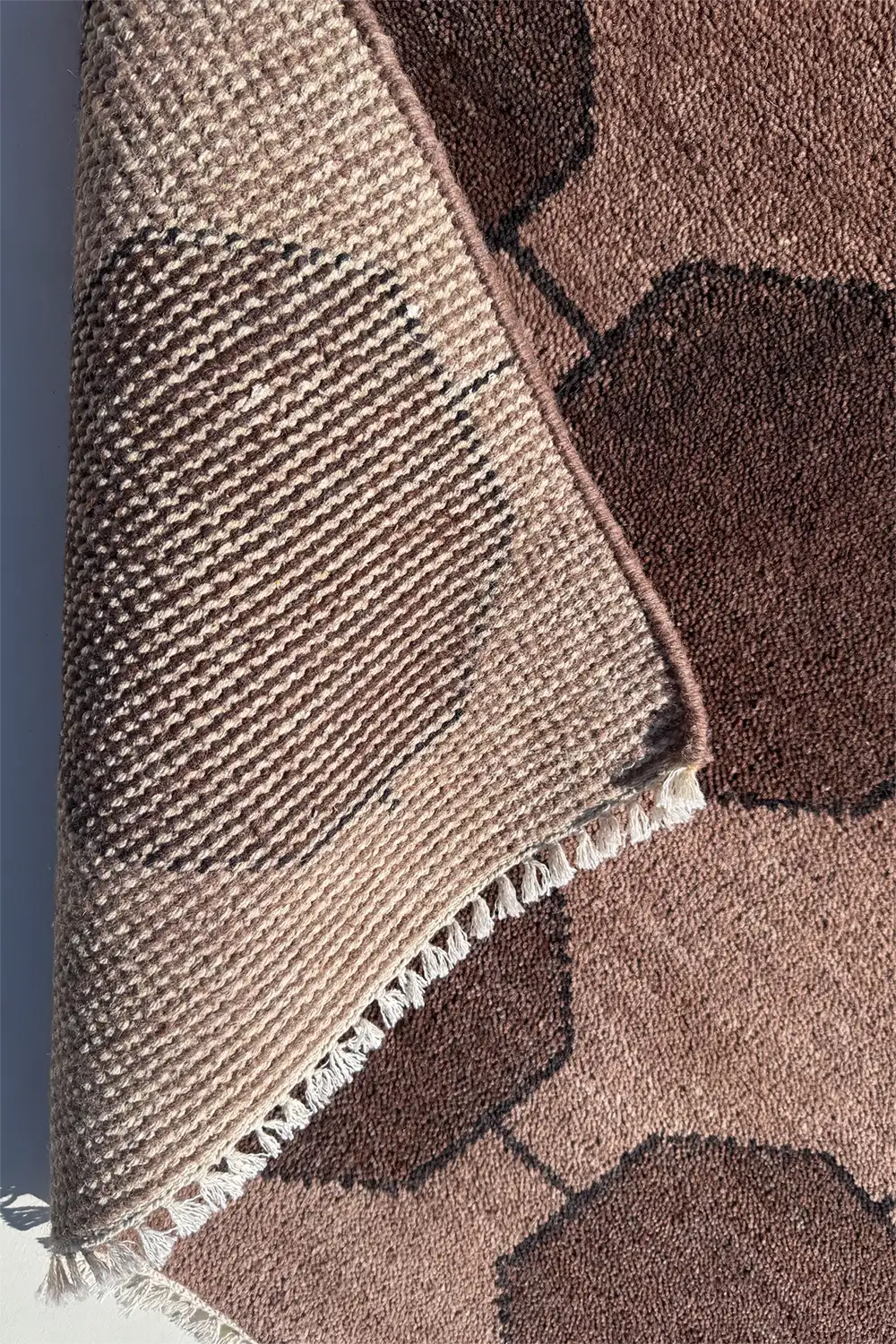 back view of dark brown wool hand-knotted luxury area rug with unique geometric design