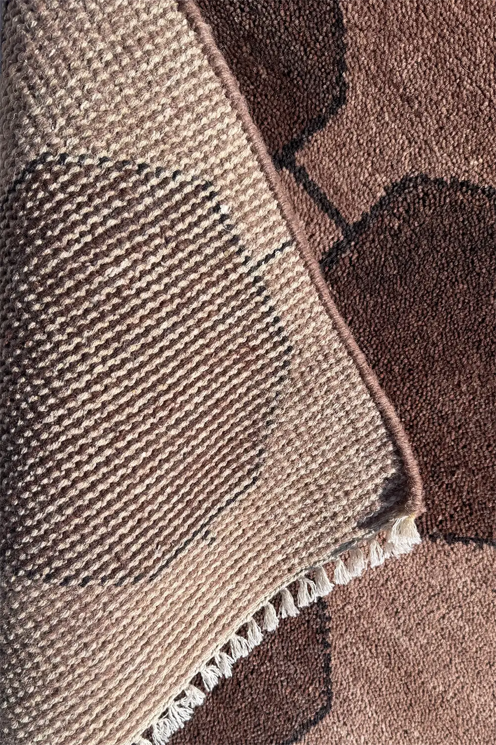 Close-up of a textured brown and beige rug with a geometric pattern.