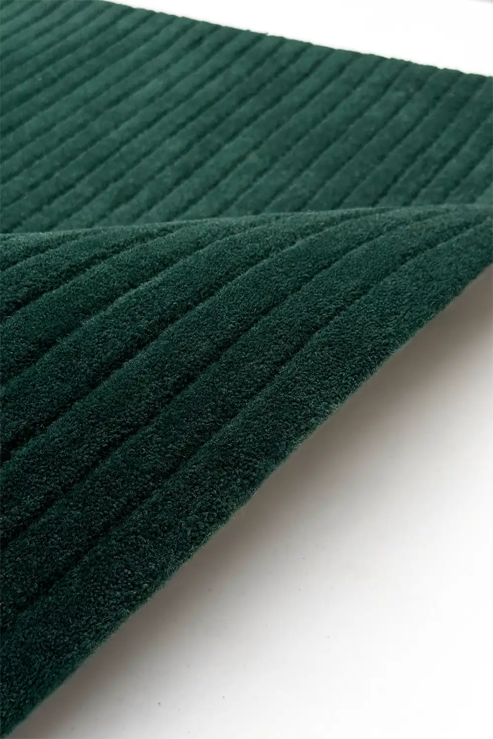 Close-up of dark green textured wool rug on a white background teal