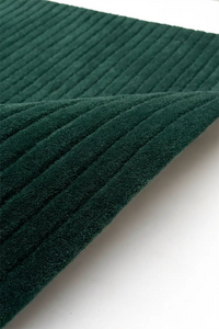 Close-up of dark green textured wool rug on a white background teal