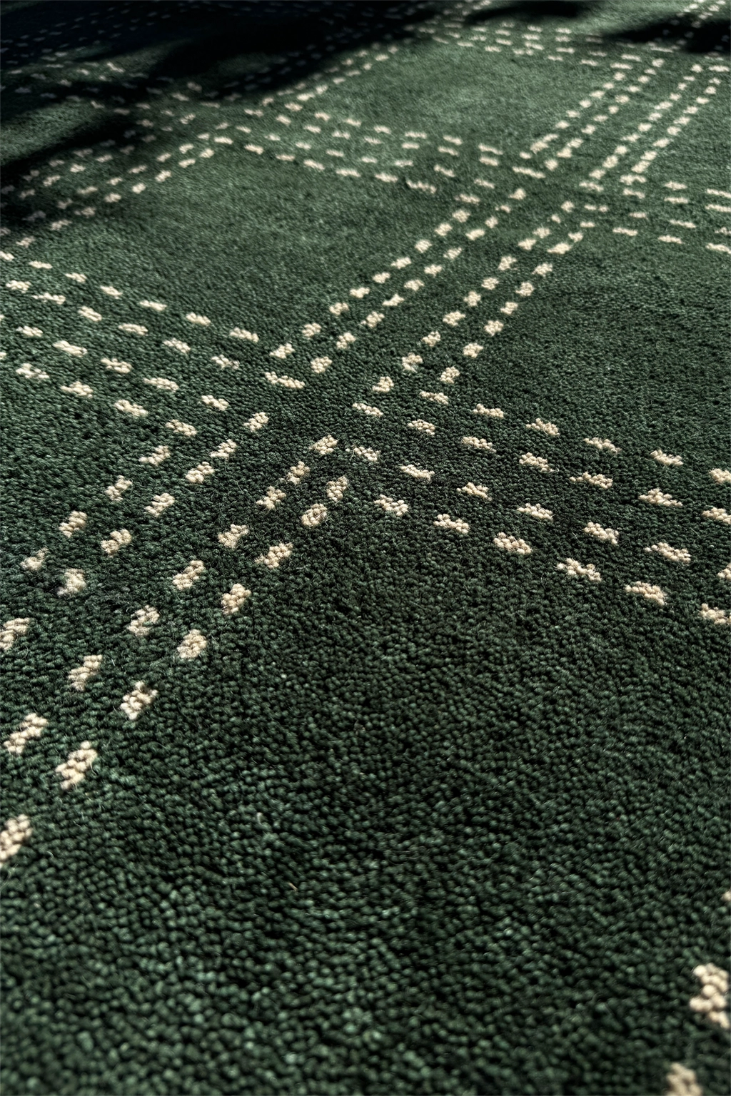 Close-up of a green rug with white geometric grid patterns