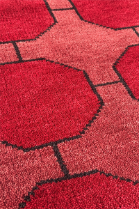 Close-up of a red geometric patterned rug with black accents