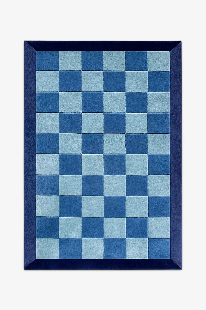 Blue checkered rug with a navy border in wool on a white background