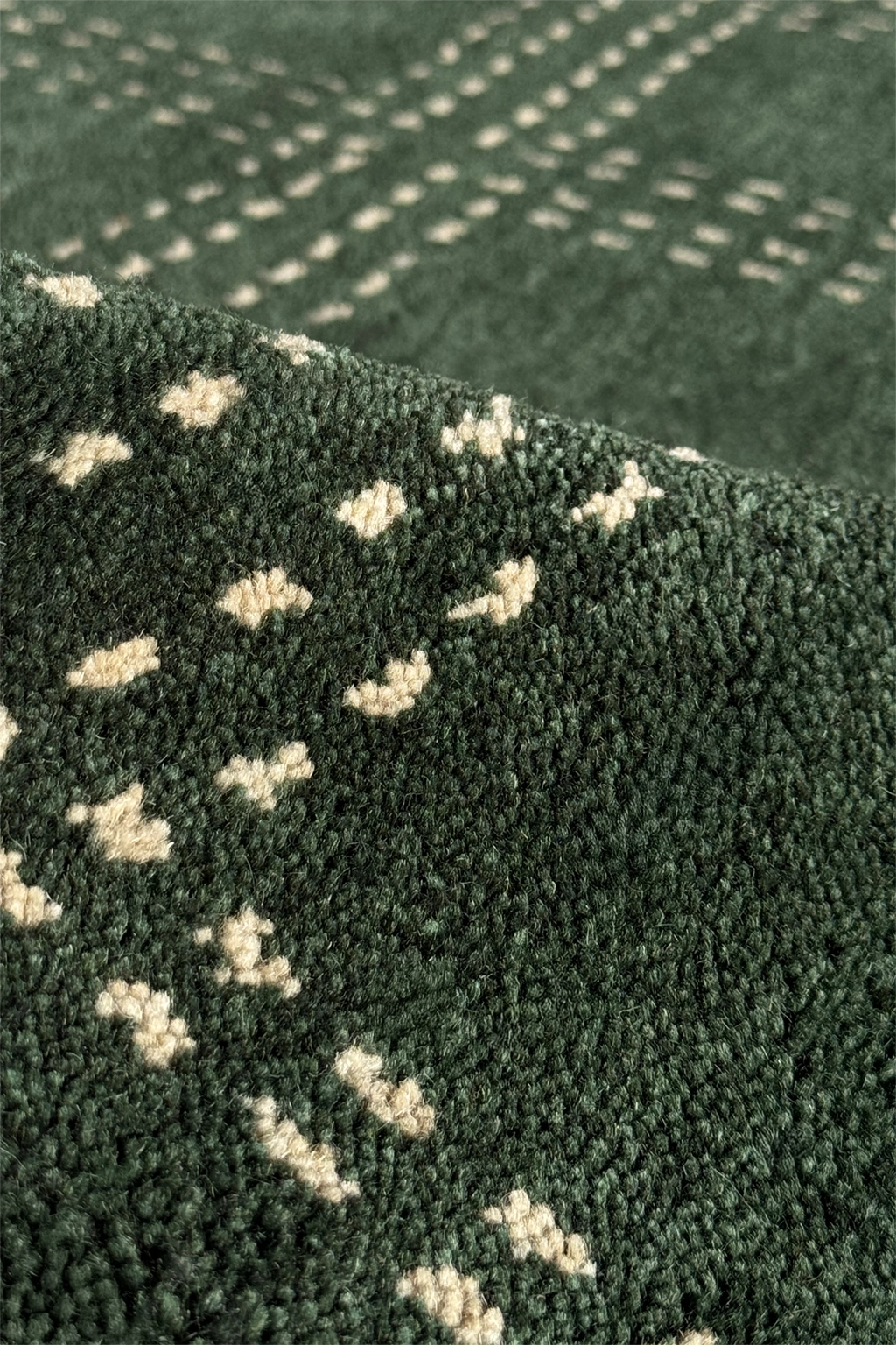 Close-up of a dark green textured runner rug with a repeating cream-colored abstract pattern, showing the pile and weave detail.