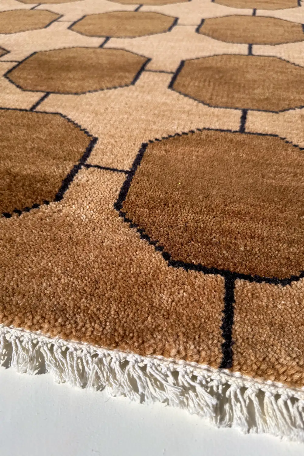Close-up of a textured modern brown rug with geometric pattern on a white background honey gold