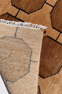 Close-up of a textured warm neutral brown and beige rug with geometric pattern and fringe honey gold