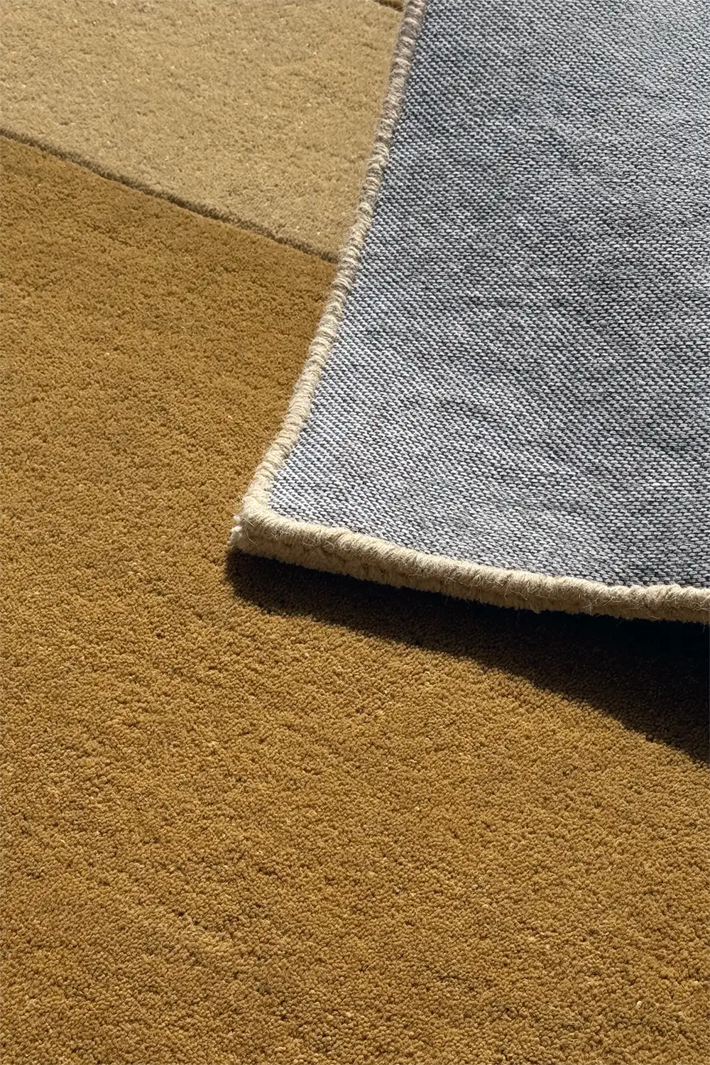 Angled corner detail of taupe, gold, and ivory carved rug, a contemporary neutral option for upscale interiors