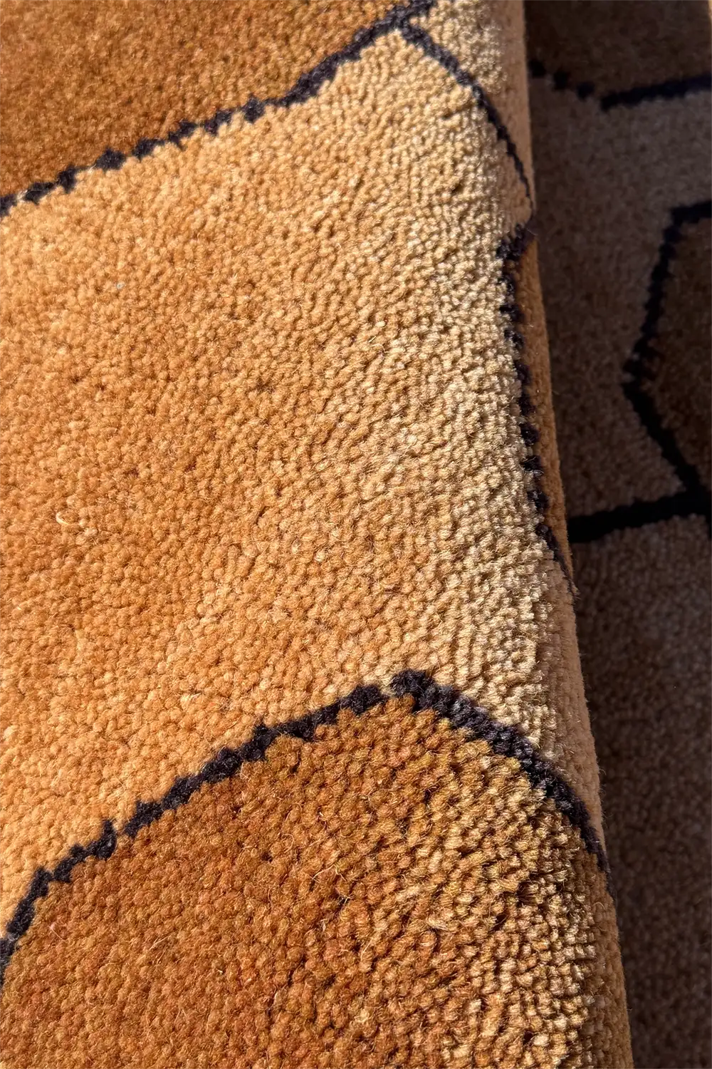 Close-up of a textured gold wool rug with geometric patterns