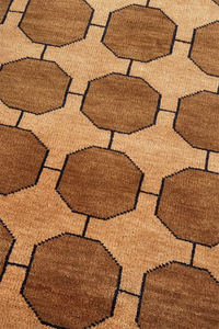 Patterned rug with honey gold brown octagonal shapes on a warm beige background
