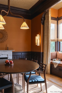 warm-toned dining room with minimalist striped gold rug, wooden table, chairs, and decorative elements.
