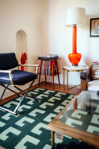modern living room with orange lamp and green geometric patterned square rug lifestyle