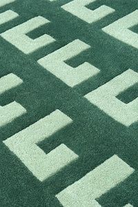 Close-up of a green and light sage geometric patterned square rug.