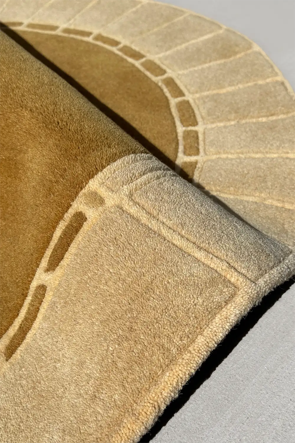Intersecting square and line motif on sculptural taupe and gold arched rug, perfect for unique living room rug styling