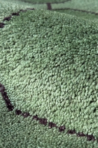 Close-up of a textured green knotted geometric rug with black accents texture