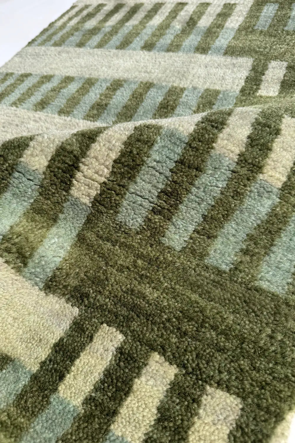 Close-up of a green and sage patterned rug hand-knotted from wool